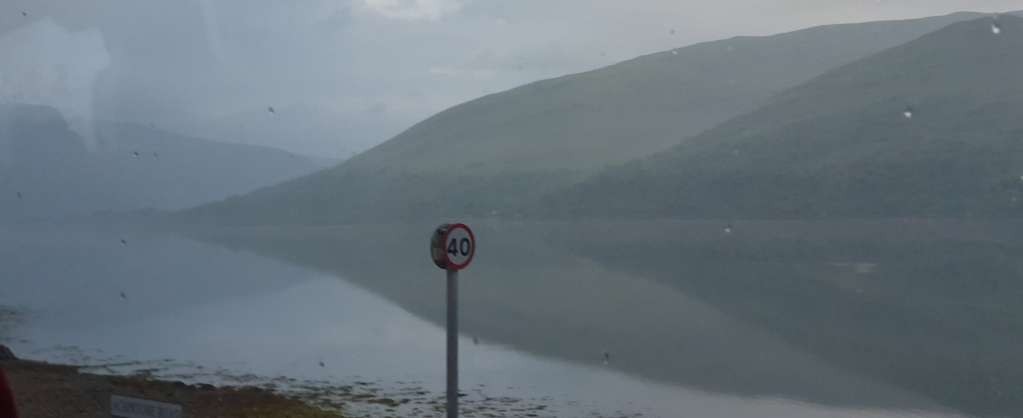 Looking at a mountain reflected on the still water of a loch.