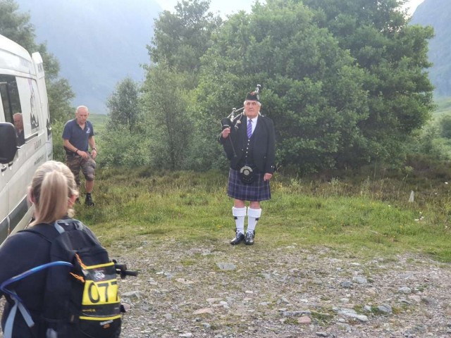 Lone piper standing in front of trees in the morning mist.