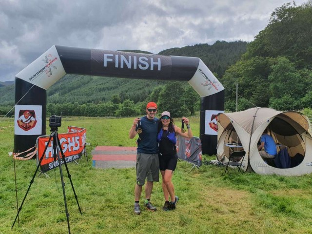 Event Finish line with couple standing with medals.