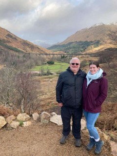 Man and woman standing in front of viaduct in Scottish Highlands
