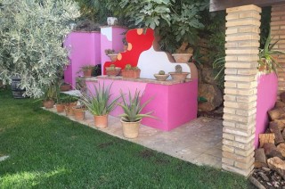 Cactus plants arranged around a bright pink shelf in a garden