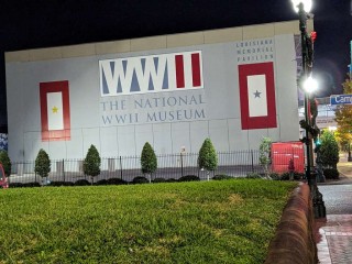 The front wall of the National WWII Museum lit up at night